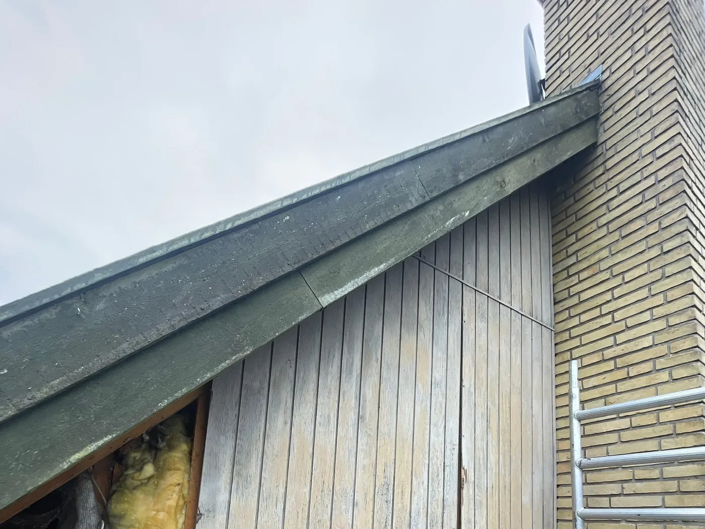 Gavl med gammel, slidt træbeklædning før udskiftning